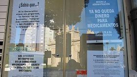 Carteles de protesta por los impagos en una farmacia de Valencia
